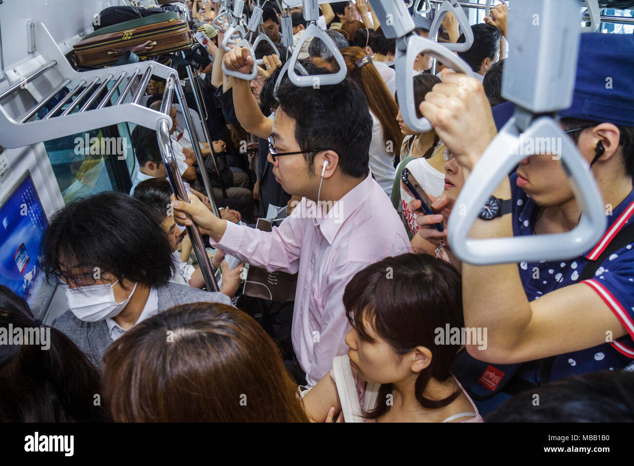 Tokyo Japan,Ikebukuro,JR Ikebukuro Station,Yamanote Line,Asian man men male adult adults,woman female women,crowded,standing,commuters,train car,strap Stock Photo