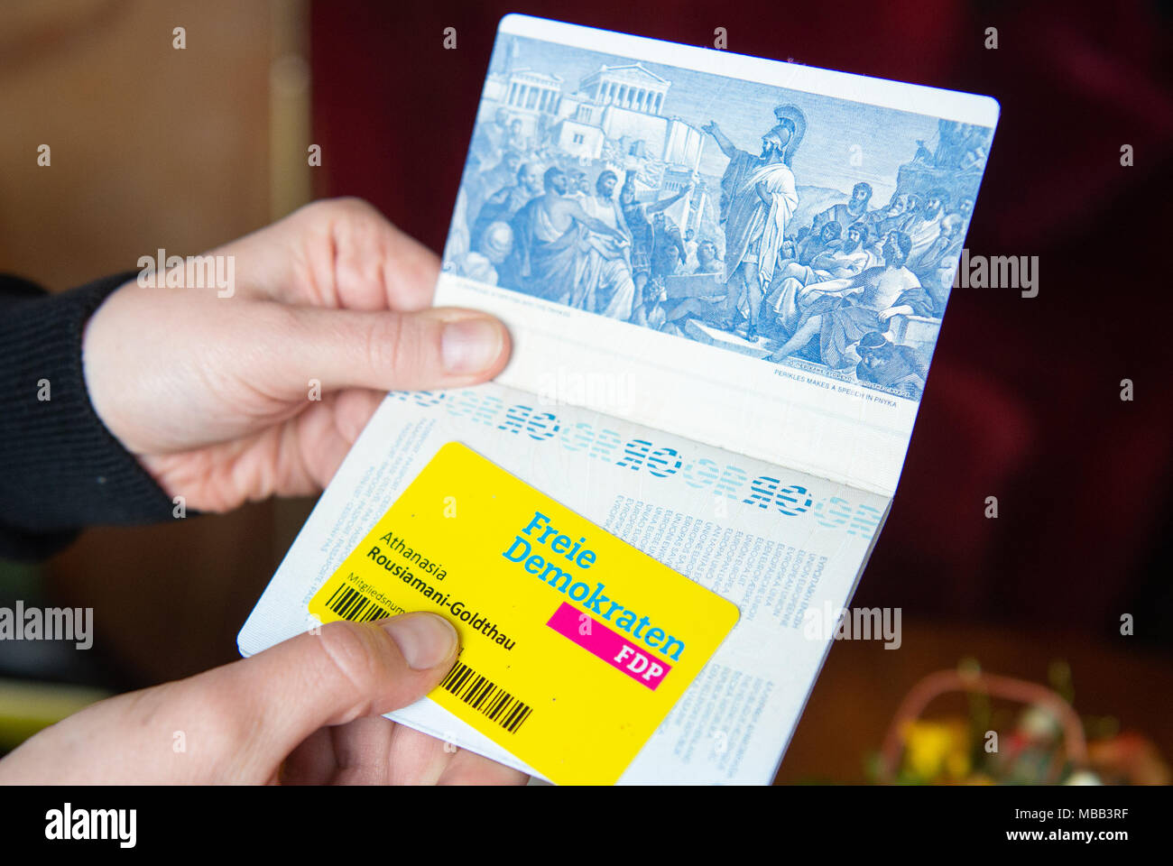 20 March 2018, Germany, Berlin: Athanasia Rousiamani-Goldthau of the Free Democratic Party (FDP), politician from Greece, holds her Greek passport and her FDP membership card in her hands. For decades she only owned the Greek passport and joined the FDP in her youth. Photo: Christophe Gateau/dpa Stock Photo