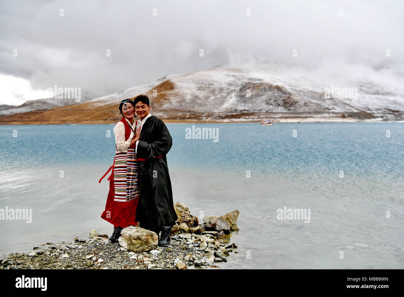 Lhasa, China's Tibet Autonomous Region. 8th Apr, 2018. Tourists pose for photos by the Yamdrok Lake in Nagarze County of Shannan City, southwest China's Tibet Autonomous Region, April 8, 2018. The Yamdrok Lake, about 100 kilometers south of the region's capital Lhasa, is one of the three holy lakes in the region. Credit: Zhang Rufeng/Xinhua/Alamy Live News Stock Photo