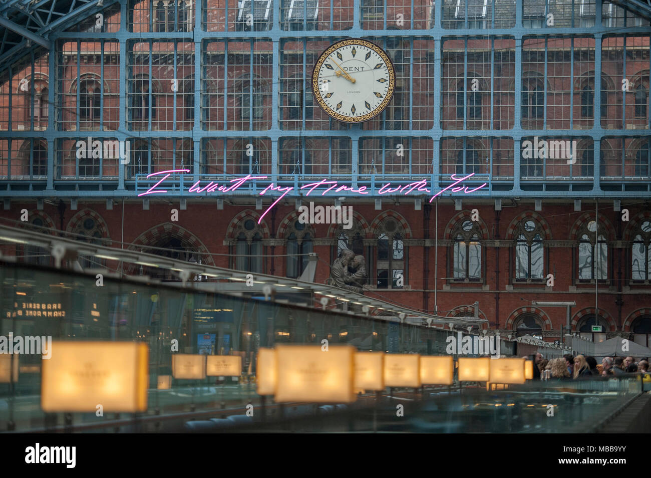 St Pancras station, London, UK. 10 April 2018. In celebration of the 150th anniversary of St Pancras International and the 250th anniversary of the RA, Tracey Emin CBE RA presents a free public Terrace Wires installation suspended from the station’s Victorian glass roof. The largest text piece she has ever made reminds travellers to stop and take a moment in one of the UK’s busiest railway stations. I Want My Time With You hangs directly below the St Pancras clock. Credit: Malcolm Park/Alamy Live News. Stock Photo