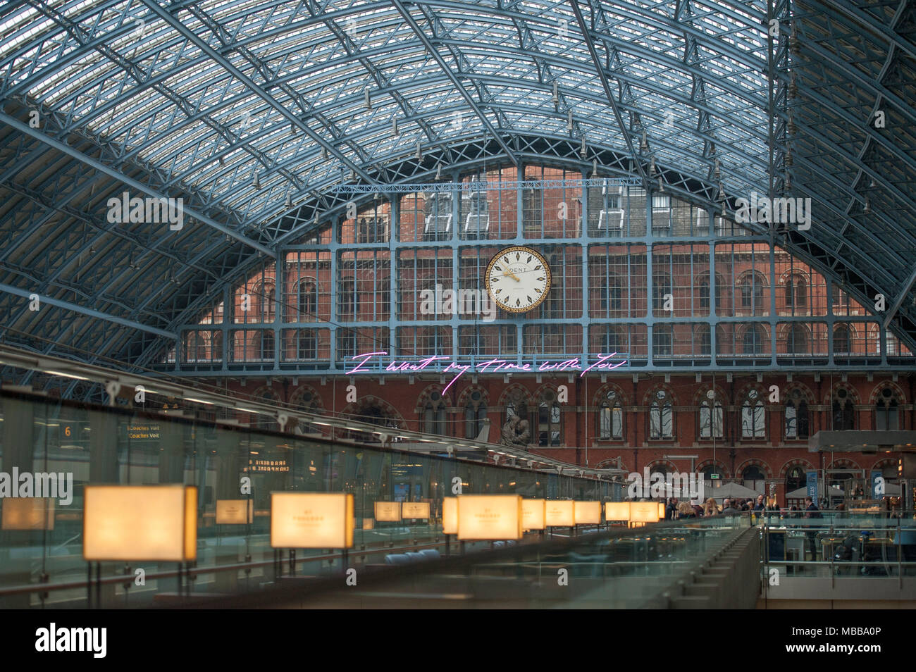 St Pancras station, London, UK. 10 April 2018. In celebration of the 150th anniversary of St Pancras International and the 250th anniversary of the RA, Tracey Emin CBE RA presents a free public Terrace Wires installation suspended from the station’s Victorian glass roof. The largest text piece she has ever made reminds travellers to stop and take a moment in one of the UK’s busiest railway stations. I Want My Time With You hangs directly below the St Pancras clock. Credit: Malcolm Park/Alamy Live News. Stock Photo