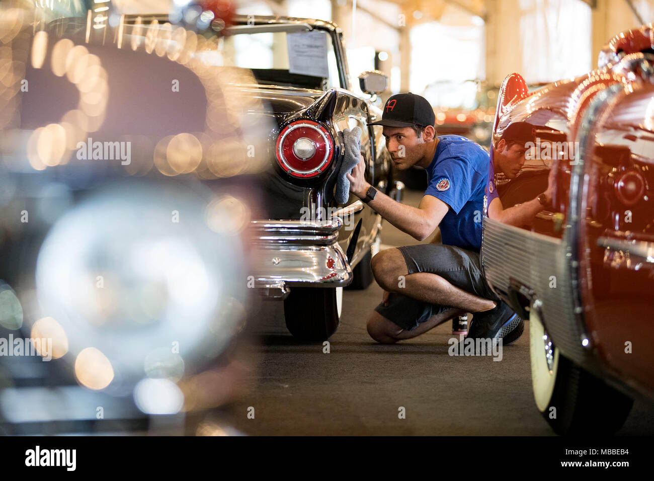 April 10, 2018 - West Palm Beach, Florida, U.S. - Kyle Martin of Adam's Polishes details a 1957 Ford Fairlane 500 Skyliner E-Code Retractable Hardtop between to Cadillac Eldorados owned by John Staluppi. Staluppi is auctioning off more than 140 cars from his Cars of Dreams Collection housed in his museum in North Palm Beach. The Barrett-Jackson auto auction runs April 12-15 at the South Florida Fairgrounds. The auto auction will last four days this year due to the number of car's Staluppi is selling. (Credit Image: © Allen Eyestone/The Palm Beach Post via ZUMA Wire) Stock Photo