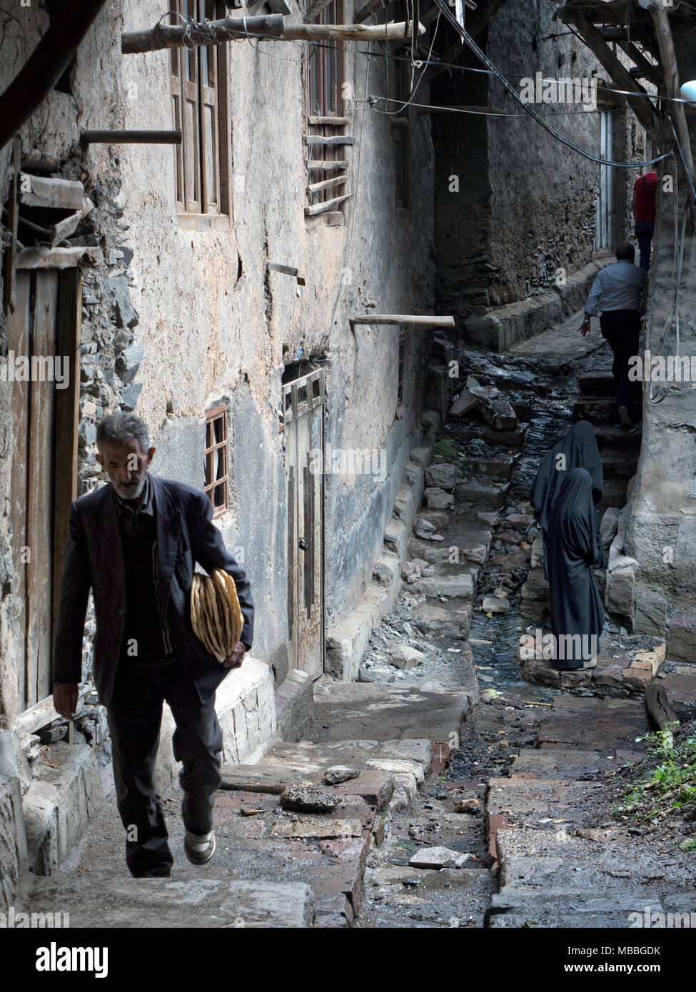 People walking in a narrow alley of Kang, historic stepped village of Razavi Khorasan province, 30km from Mashhad Stock Photo
