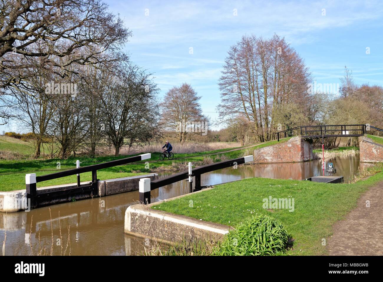 Elderly male cyclist by the River Wey navigation at Walsham lock on a sunny spring day,Ripley Surrey England UK Stock Photo