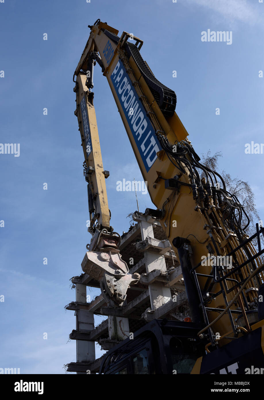Caterpillar 360 high reach demolition excavator with concrete crusher attachment  in front of partly demolished concrete building bury lancashire uk Stock Photo