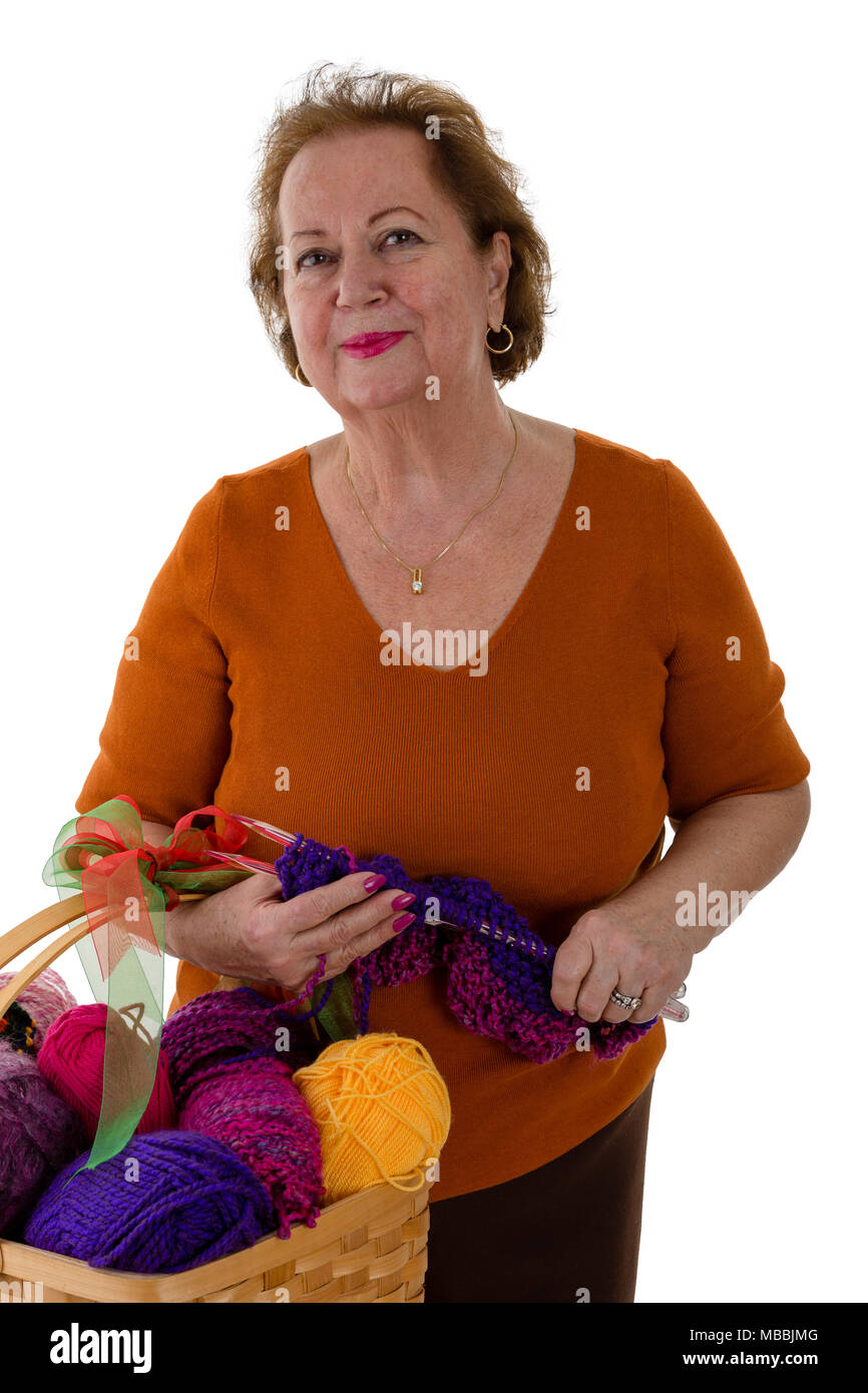 Portrait of senior woman standing with knitting accessories against white background Stock Photo