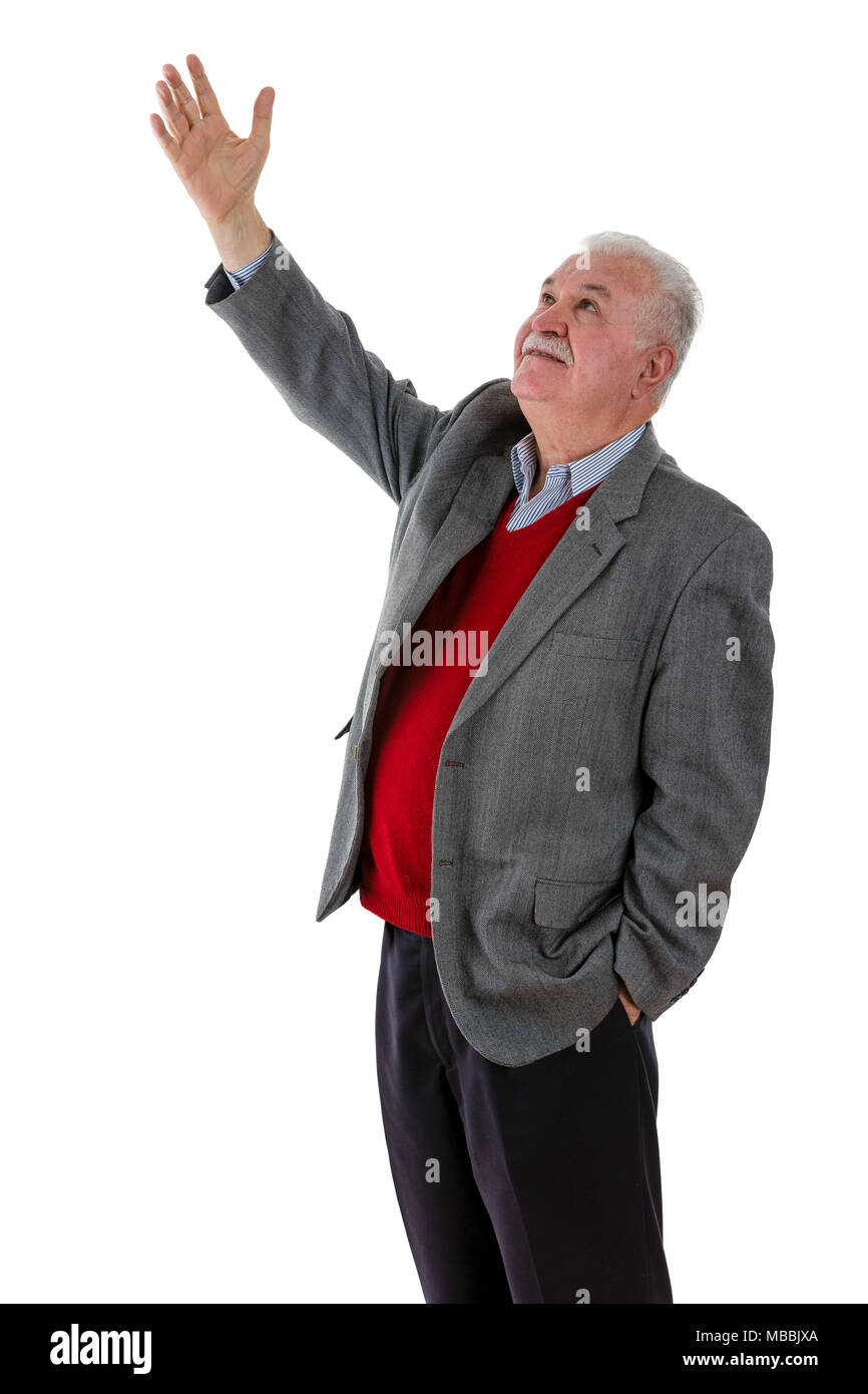 Elderly retired man raising his hand in the air above his head as he looks up with a serious thoughtful expression on white Stock Photo