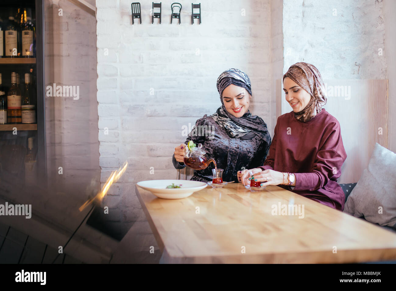 two caucasian muslim woman drinking tea in cafe Stock Photo