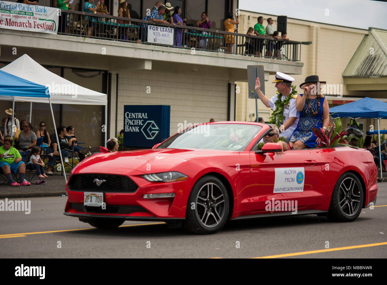 HILO, Hawaii (April 7, 2018) -- Rear Adm. Brian Fort, Commander Navy Region Hawaii, and his wife  greet spectators during the Merrie Monarch Festival Parade in downtown Hilo on Saturday April 7. Fort along with the Pacific Fleet Band, participated in the parade. The Navy recognizes that the Merrie Monarch Festival honors the legacy left by King David Kalākaua, who inspired the perpetuation of Hawaiian traditions, native language and arts. King Kalākaua negotiated a treaty with the United States that led to the Navy’s presence at Pearl Harbor. (U.S. Navy Photo by Mass Communication Specialist 1 Stock Photo