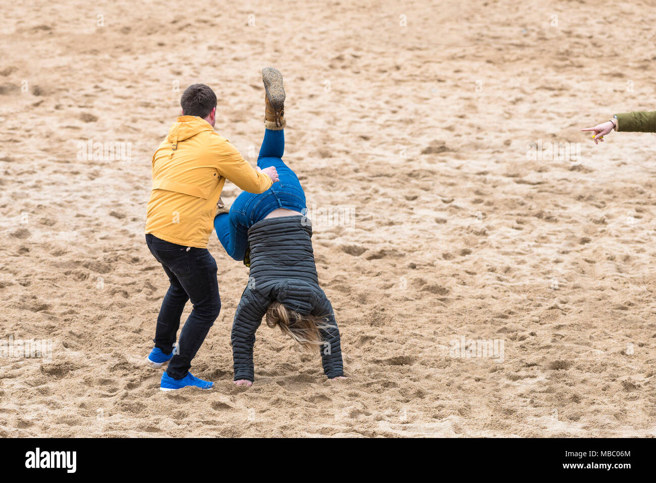 A man trying to help his wife perform a handstand on Fistral Beach in Newquay Cornwall. Stock Photo