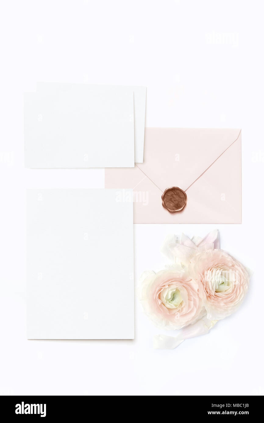 Feminine wedding, birthday desktop mock-ups. Blank greeting cards, envelope with seal and pink Persian buttercup flowers. White table background, flat Stock Photo