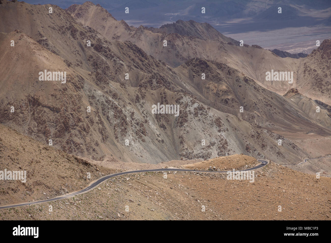 Full of switchbacks and dramatic bends, the road to Khardung Pass is not for the faint of heart. There is no vegetation to bind rocks above and below. Stock Photo