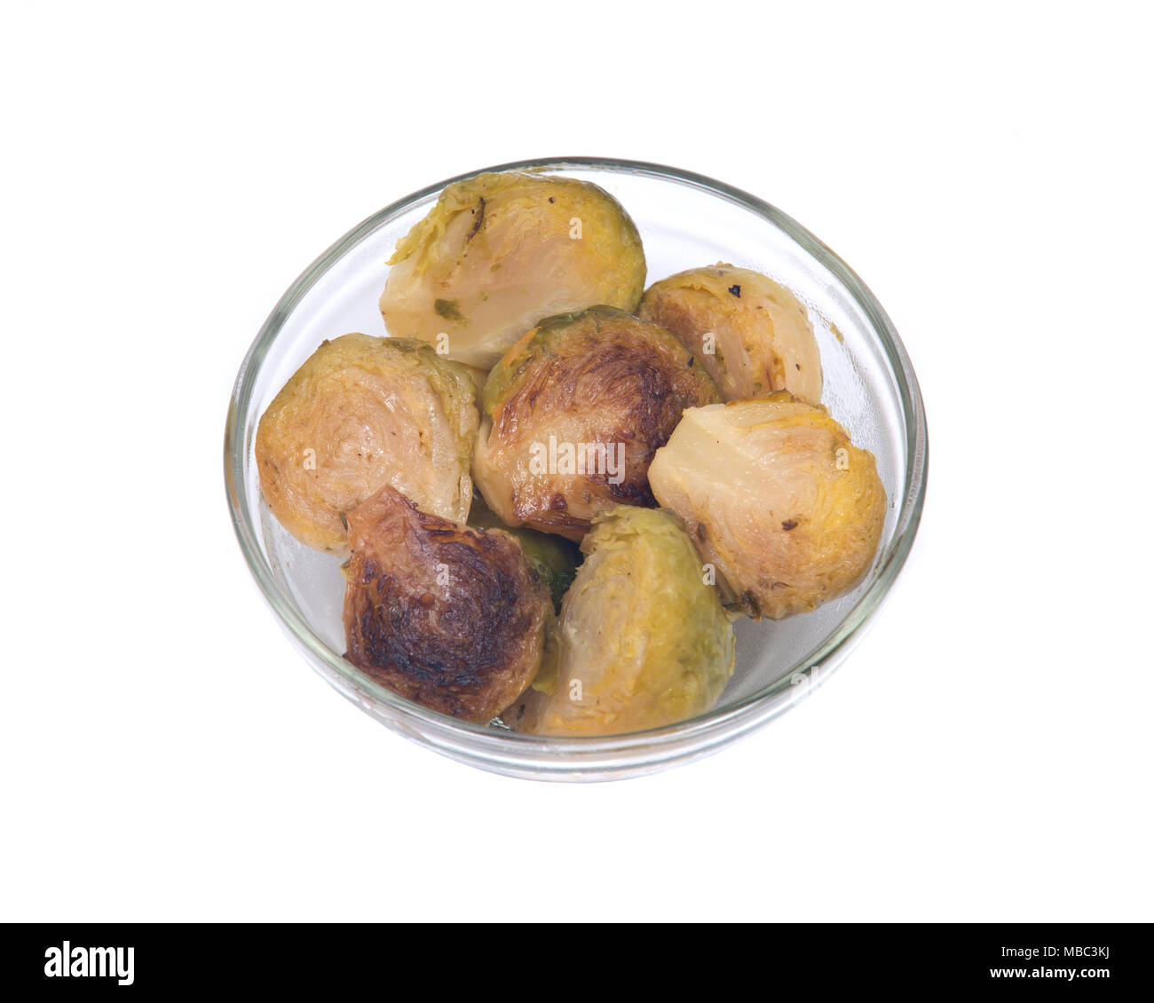 Roasted brussels sprouts in clear glass dish isolated on white background Stock Photo