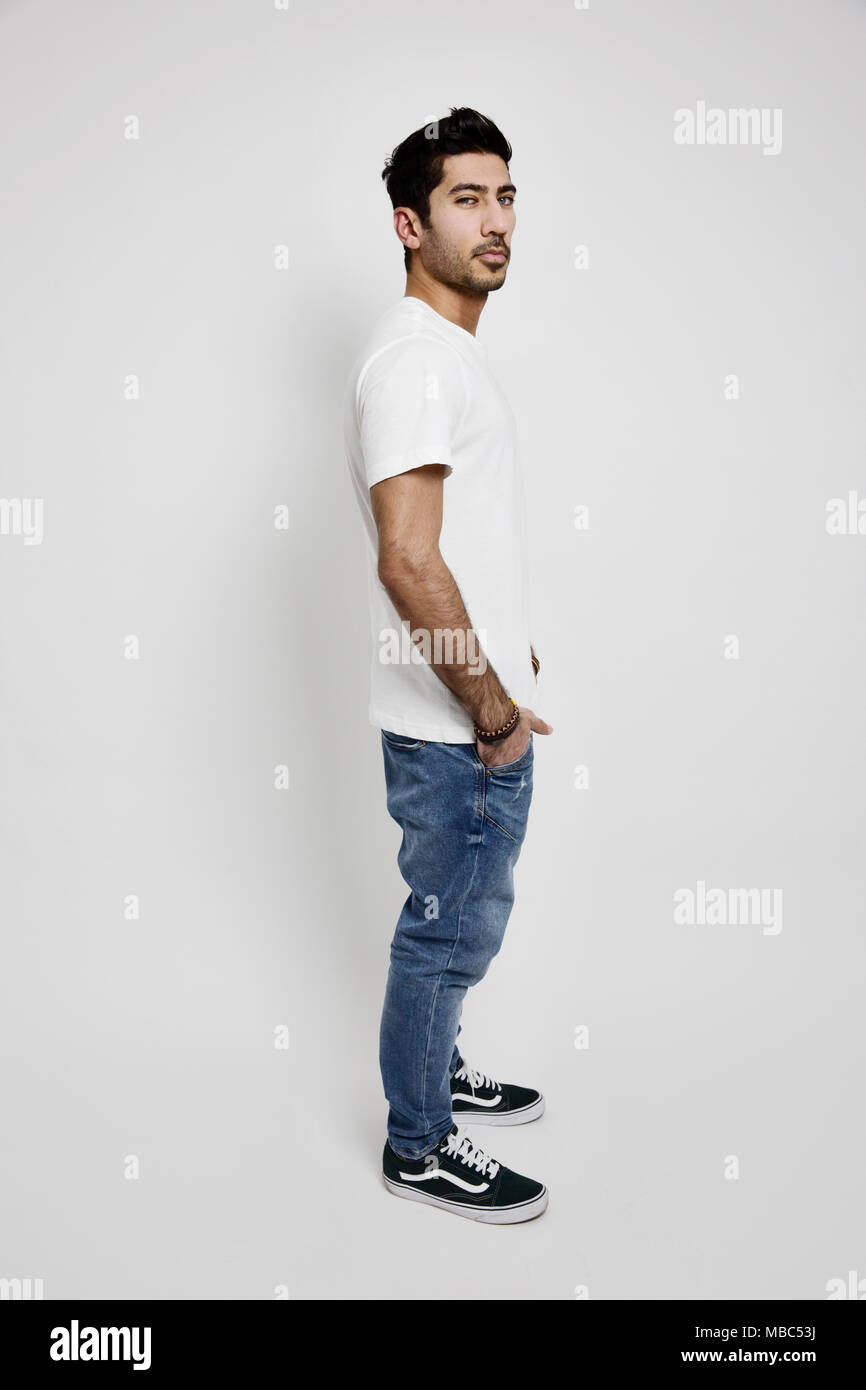 Young man, white T-shirt, jeans and sneakers, studio shot Stock Photo