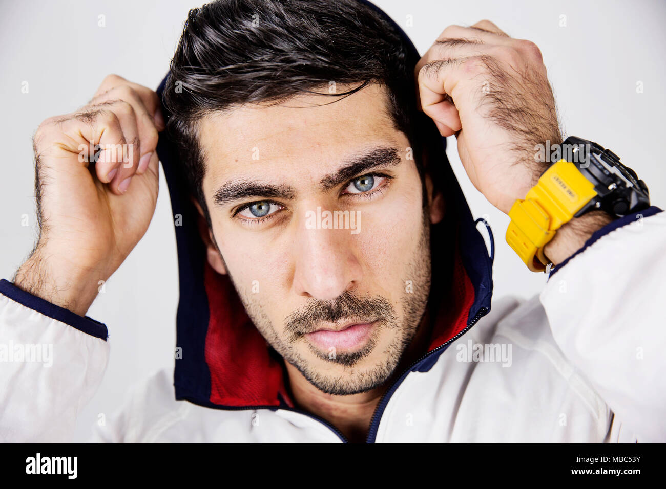 Young man, sporty hooded jacket and modern watch, portrait, studio shot Stock Photo