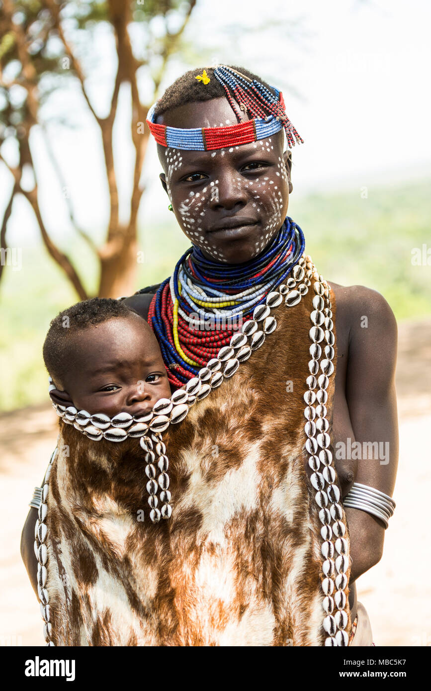 Young woman with toddler in traditional clothes made of goatskin, Karo tribe, Southern Nations Nationalities and Peoples' Region Stock Photo