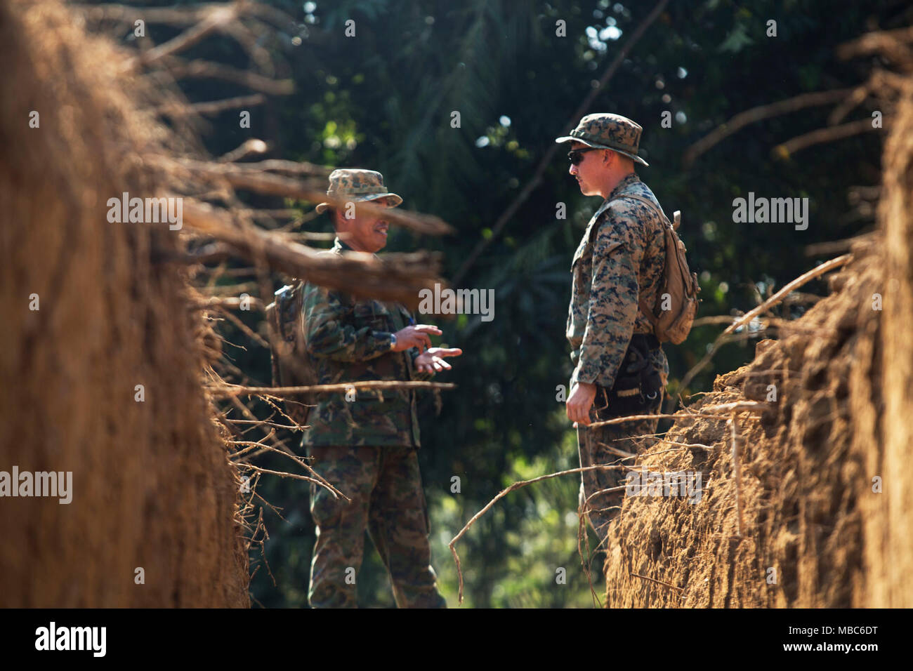 U.S. Marine Cpl. Michael Troll, a native of Charlotte, North Carolina, discusses the design of a trench with a combat engineer from the Kingdom Thailand at Camp Ban Chan Khrem, Thailand, Feb. 14, 2018. U.S. Marines are working alongside Thai engineers to build low-water crossings to allow vehicles and emergency personnel to travel effectively during Thailand’s rain season. Troll is the lead combat engineer for Combat Logistics Battalion 4, 3rd Marine Logistics Group, during the subject matter expert exchange between combat engineers from the U.S. and the Kingdom of Thailand during Exercise Cob Stock Photo