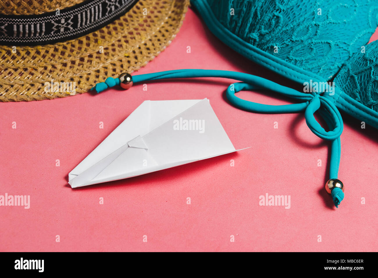Swimsuit, Hat, Papercraft Plane on Pink Background. Travel Concept with Copyspace. Stock Photo