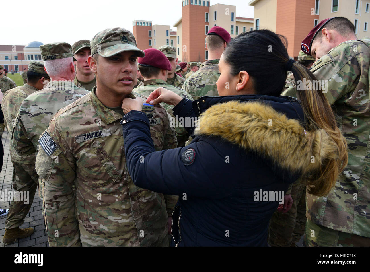 A U.S. Army Paratrooper, assigned to the 173rd Airborne Brigade, is pinned by his spouse during the Expert Infantryman Badge (EIB) ceremony at Caserma Del Din, Vicenza, Italy, 15 Feb. 2018. (U.S. Army Stock Photo