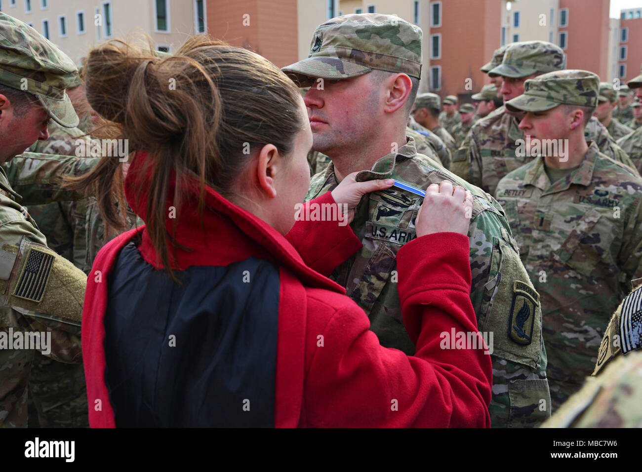 A U.S. Army Paratrooper, assigned to the 173rd Airborne Brigade, is pinned by his spouse during the Expert Infantryman Badge (EIB) ceremony at Caserma Del Din, Vicenza, Italy, 15 Feb. 2018. (U.S. Army Stock Photo