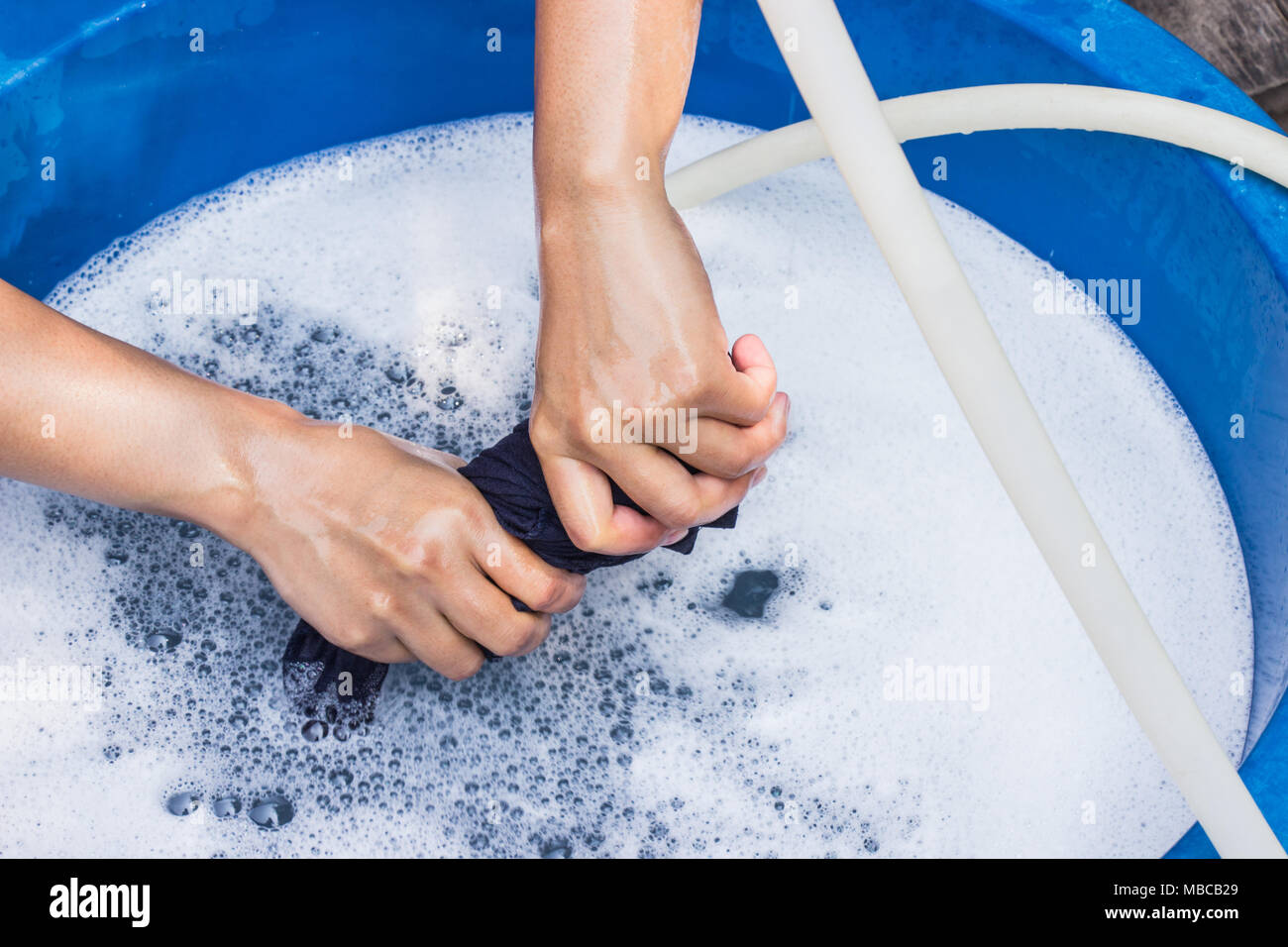 Female hands wash clothing by hand with detergent in basin. selective focus and space for text. Stock Photo