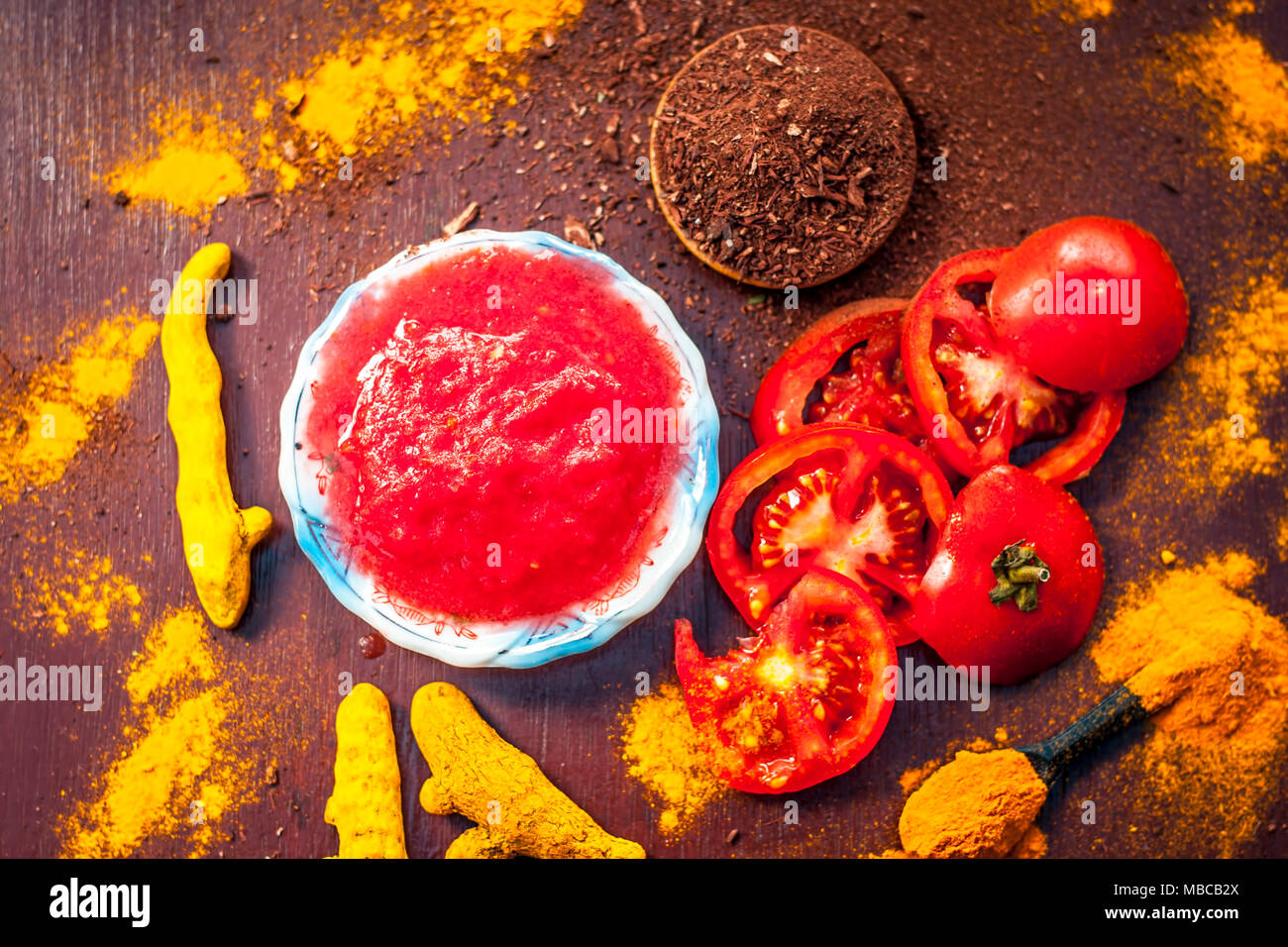 Close up of Tomato puree,sandalwood,turmeric and its powder on a wooden surface.It is used to clear the dark heads and black skin. Stock Photo
