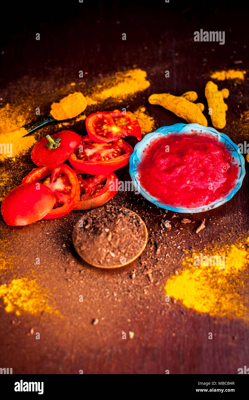 Close up of Tomato puree,sandalwood,turmeric and its powder on a wooden surface.It is used to clear the dark heads and black skin. Stock Photo
