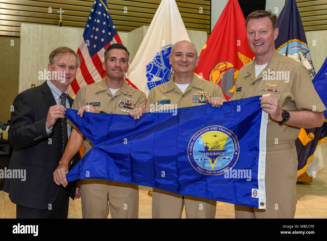 Fla. (Feb. 20, 2018) Rear Adm. Kyle Cozad (far right), commander, Naval Education and Training Command (NETC), presents the 2017 NETC Training Excellence Award blue burgee to Capt. Bill Lintz (second from right), commanding officer, Center for Information Warfare Training (CIWT). CIWT won the overall Training Excellence White 'T' award, all nine functional area awards and is authorized to display the burgee throughout 2018. Also pictured are John Jones, NETC’s executive director (far left), and CIWT Command Master Chief Mike Bates (second from left). (U.S. Navy Stock Photo