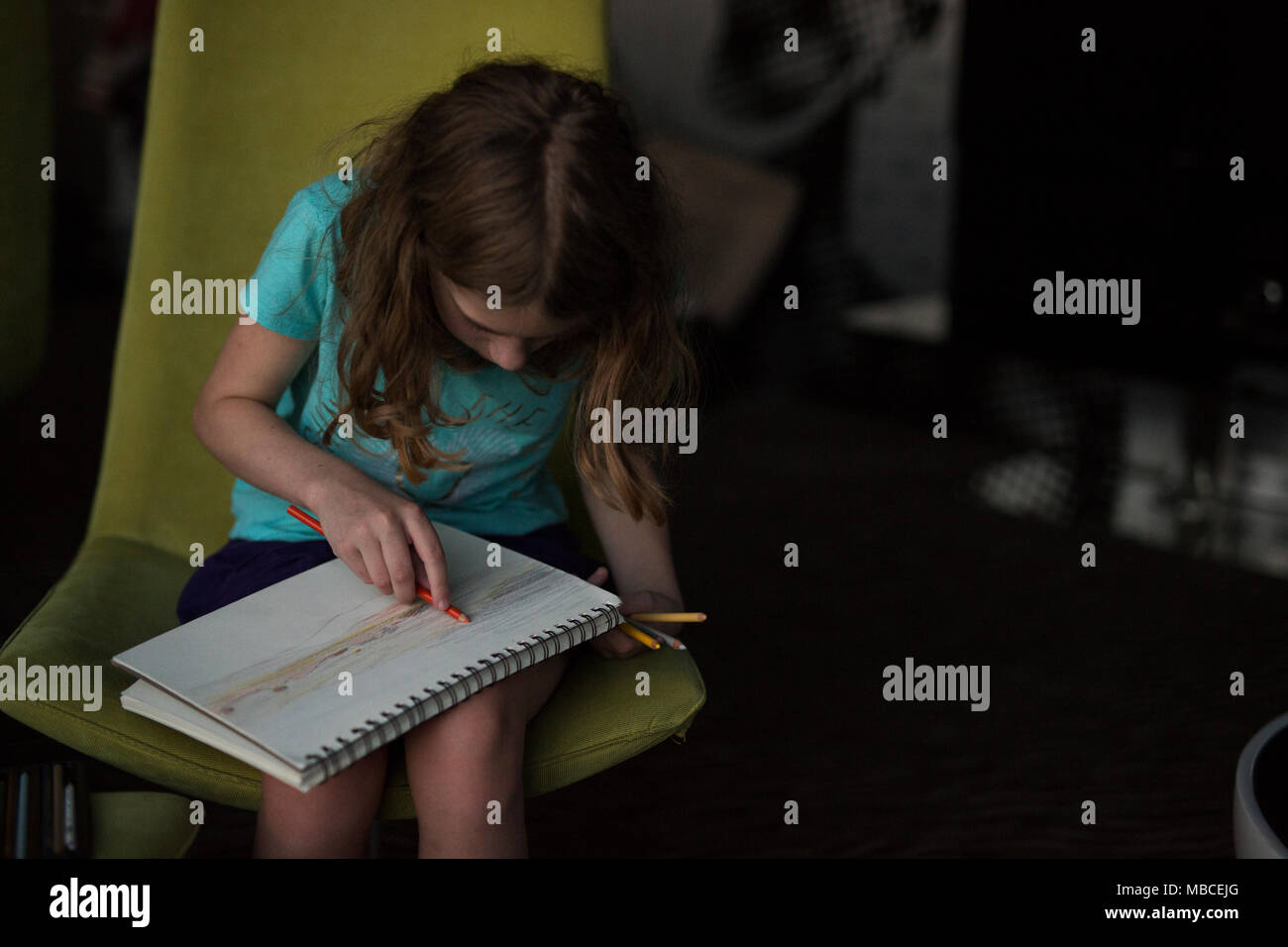 An eleven-year-old tween girl drawing the sunset in a hotel room in Brno, Czech Republic. Stock Photo