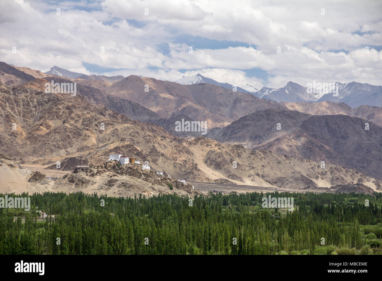 Looking across floodplain of river Indus to Thiksay Monastery.  Perched on a steep rocky outcrop, the monastery is still low compared to mountains Stock Photo