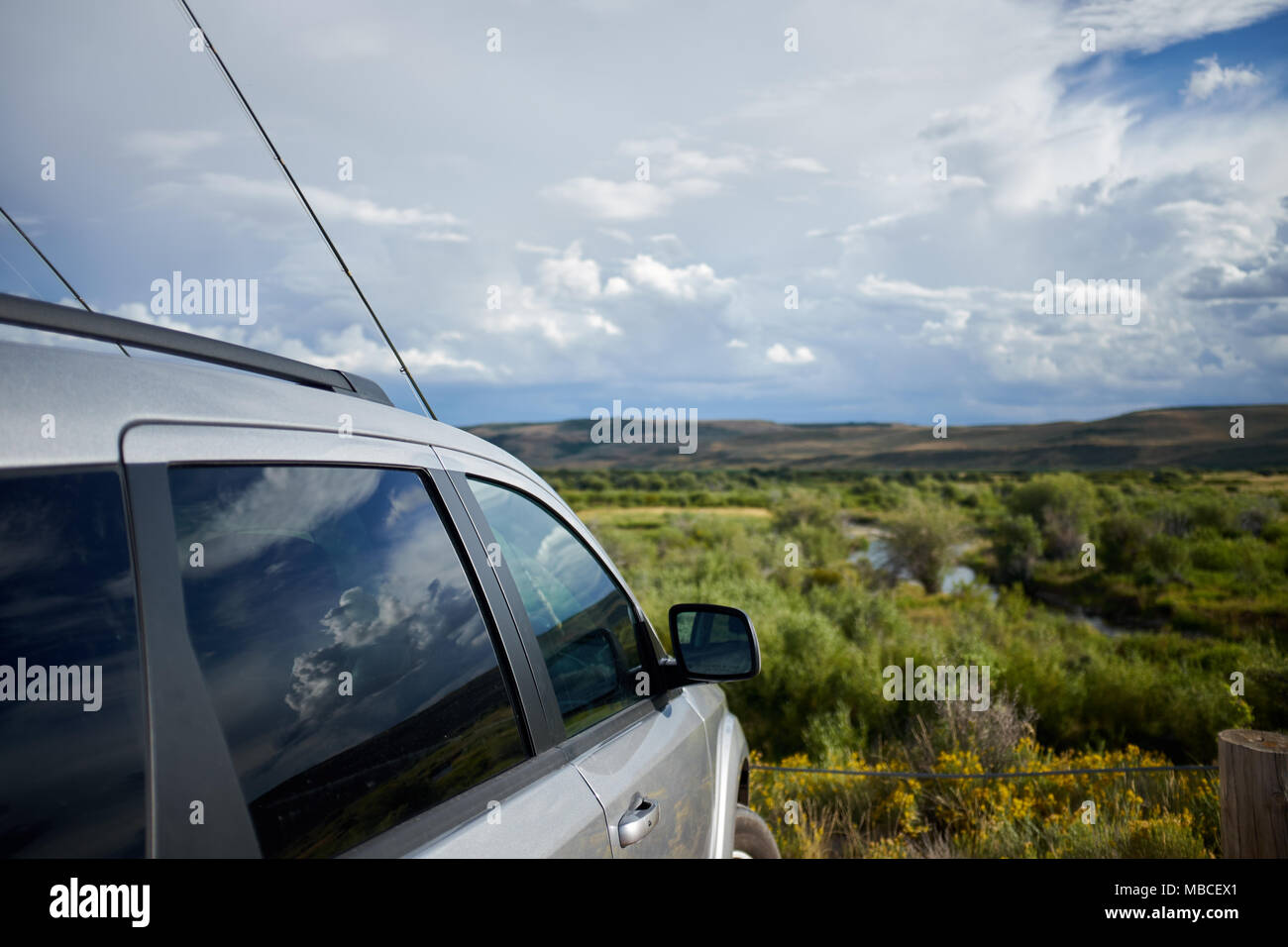 Car parked overlooking the Hams Fork River, Wyoming with two fly fishing  rods resting on the bonnet or hood on a cloudy day Stock Photo - Alamy