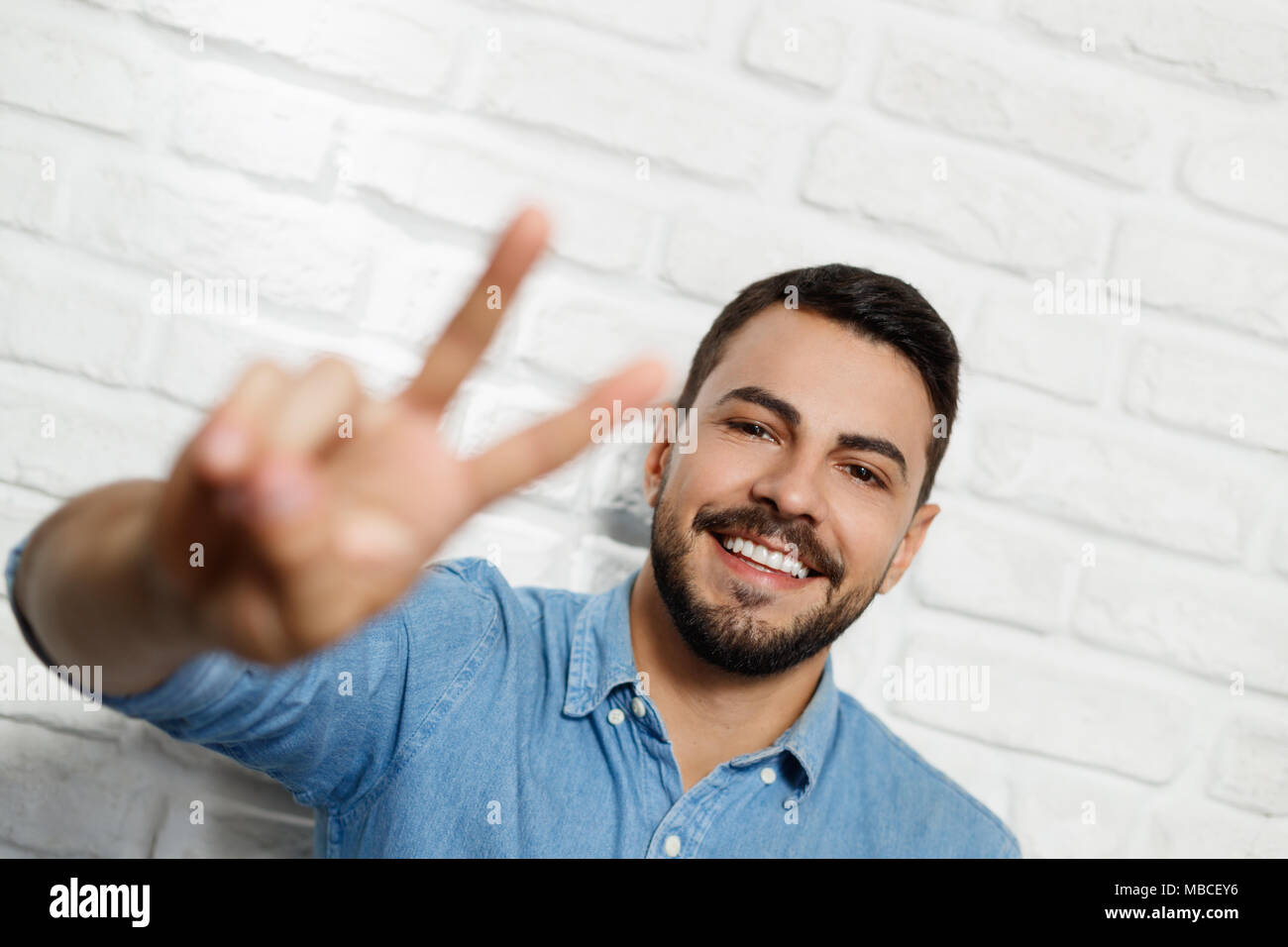 Facial Expressions Of Young Beard Man On Brick Wall Stock Photo