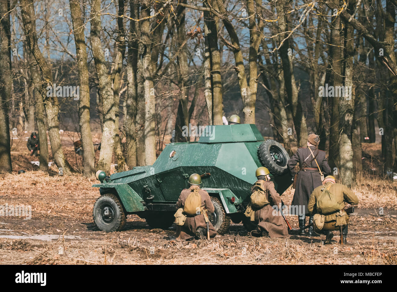 Group Of Reenactors Dressed As Russian Soviet Red Army Soldiers Of World War II Go On Offensive Under Cover Of Armored Soviet Scout Car Ba-64. Histori Stock Photo