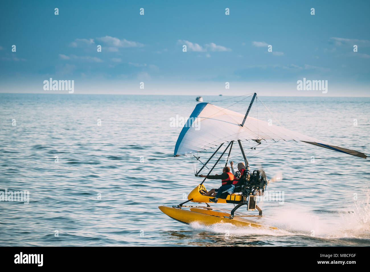 Motorized Hang Glider With Muslim Woman Take Off Frow Sea In Sunny Summer Day. Muslim People Having Fun Stock Photo