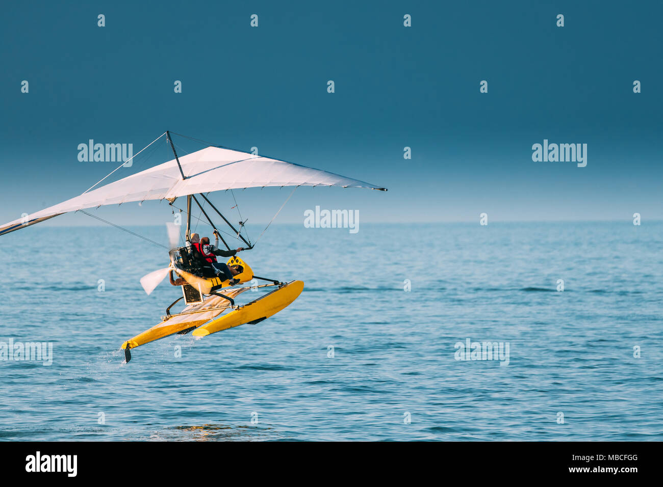 Motorized Hang Glider With Muslim Woman Take Off Frow Sea In Sunny Summer Day. Muslim People Having Fun Stock Photo