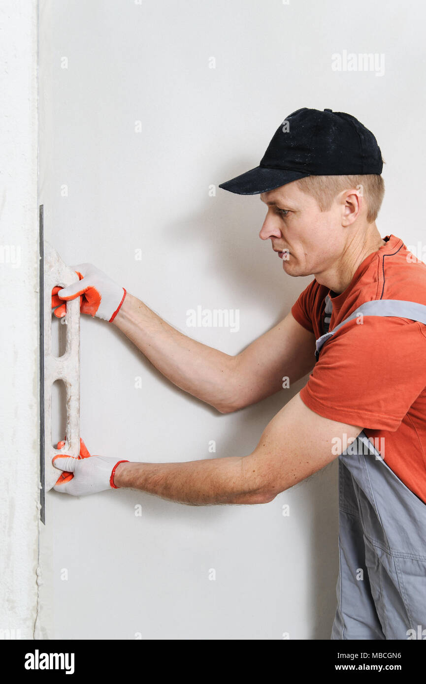 The worker puts f inishing layer of stucco on the wall using a plastering trowel Stock Photo