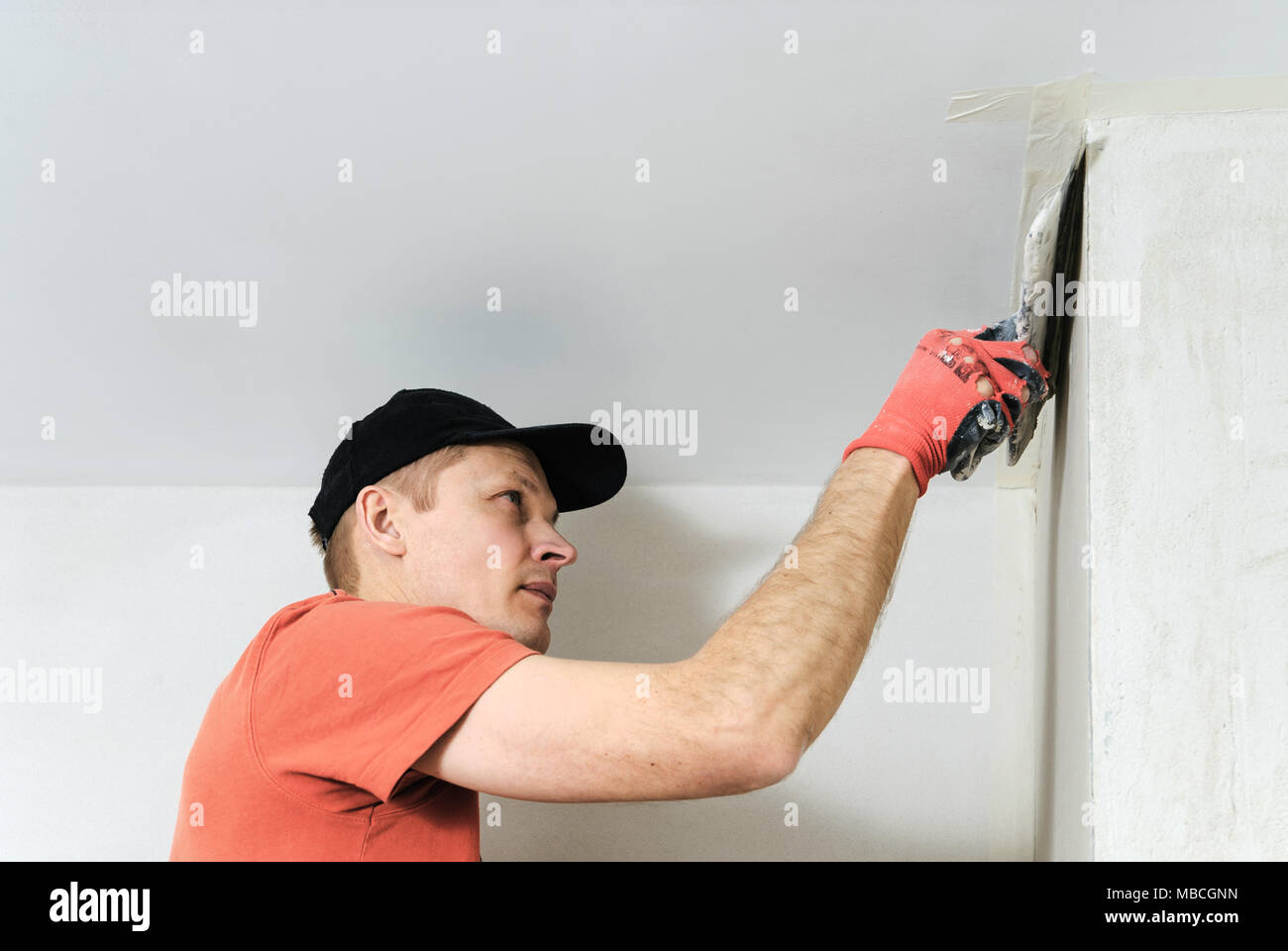 вешайте коврики на сухую штукатурку. вешать на сухую штукатурку. мужчина в каске штукатурит. вицин живопись. человек использует штукатурку.