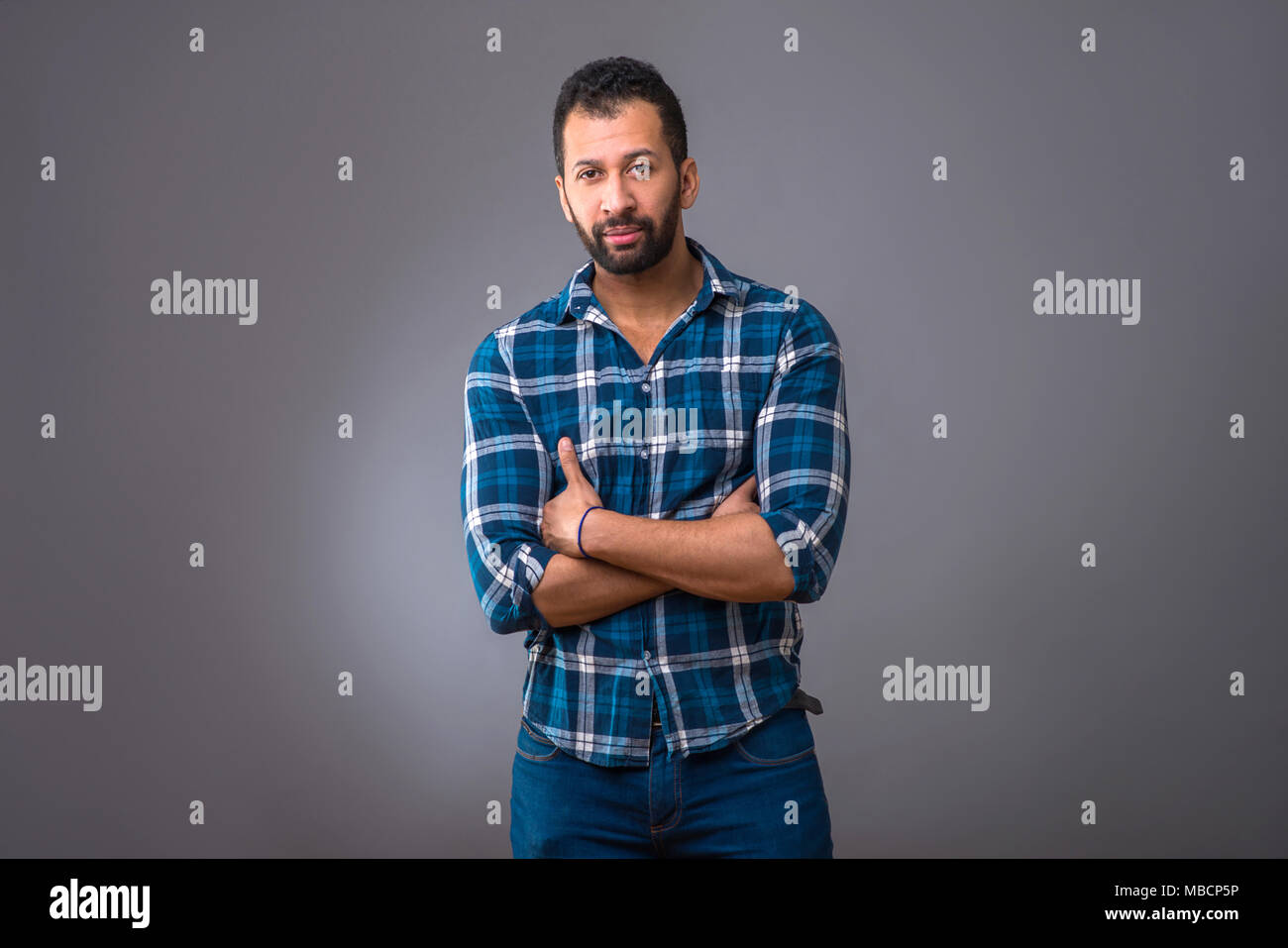 A serious young black man standing confidently with his arms folded Stock Photo