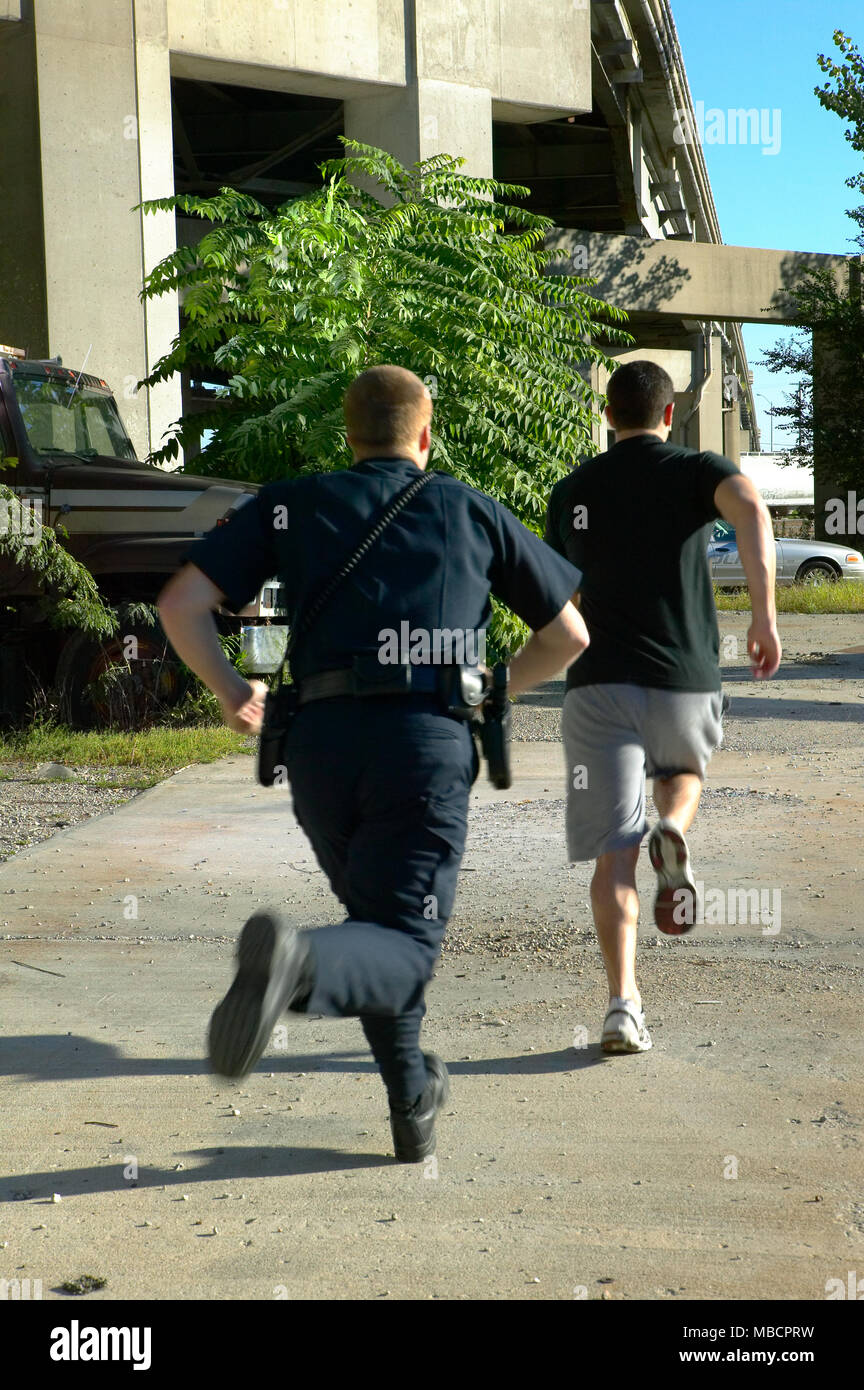 Policeman chasing after running away suspect man Stock Photo - Alamy