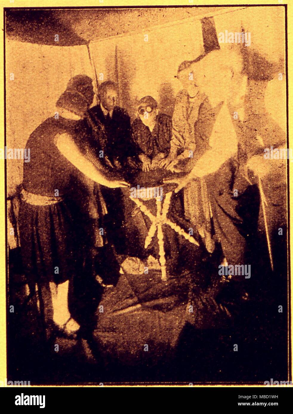 Seance. Levitating trumpet etc. Flash photo taken during a Warrick-Deane seance of 5th September 1929, showing hands resting upon a strongly levitating table. Stock Photo