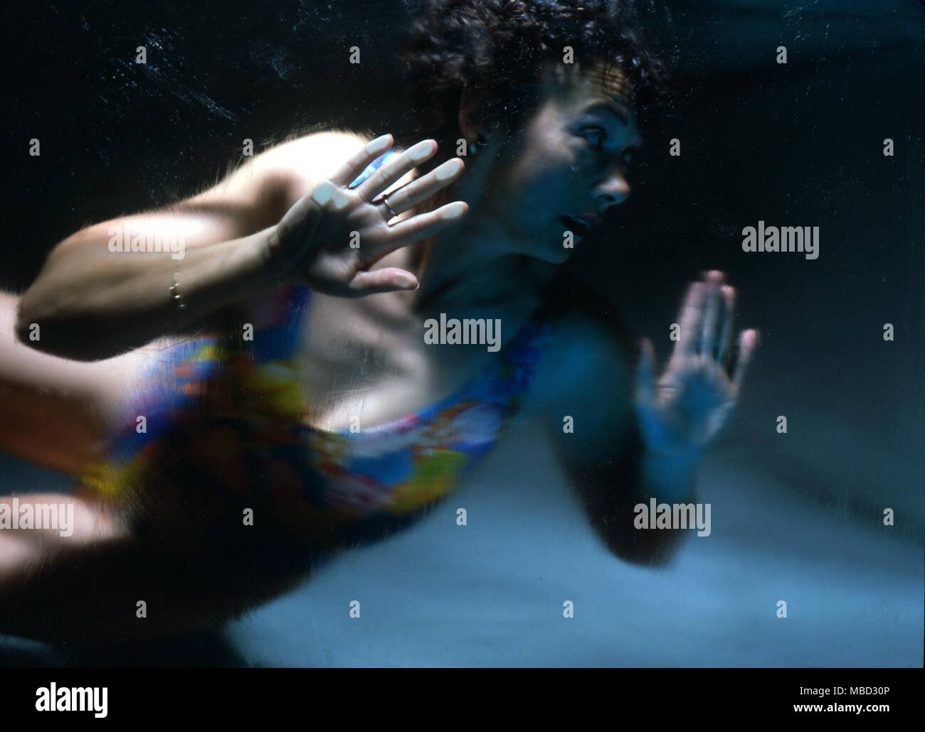 Stage Magic - Drowning Girl. Girl in swimming costume, locked in a glass cabinet which is rapidly filling with water. Apparently she has no escape. Stock Photo