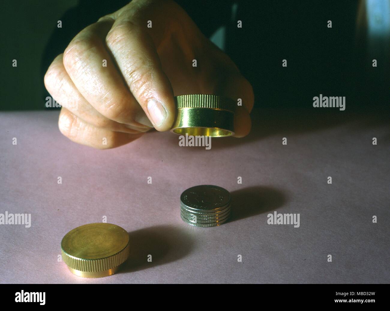 Stage Magic - Marvin's Magical Coins. Magician prepares to make coins vanish. Stock Photo