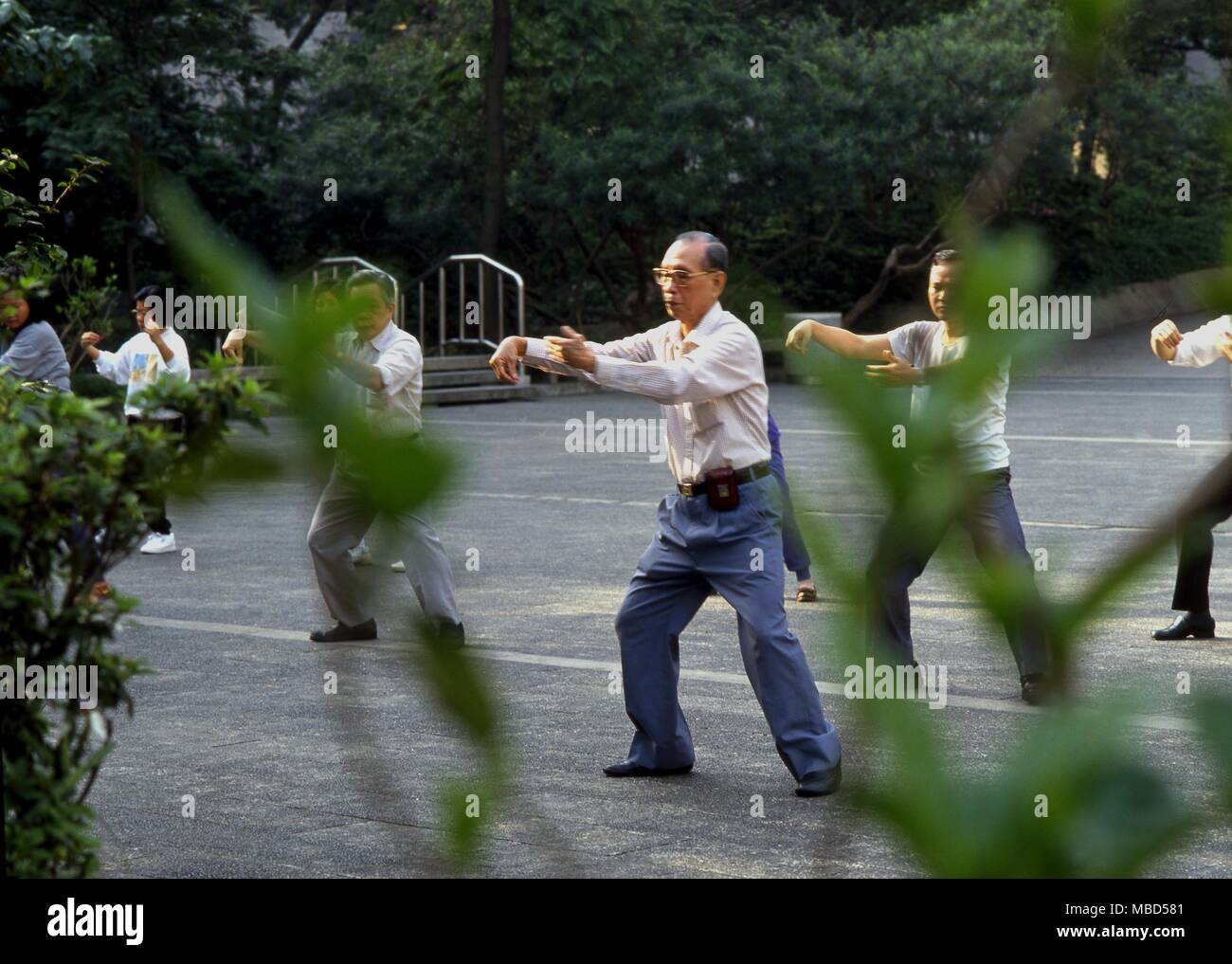 Chinese master of Tai Chi with his students in a park in Hong Kong Stock Photo