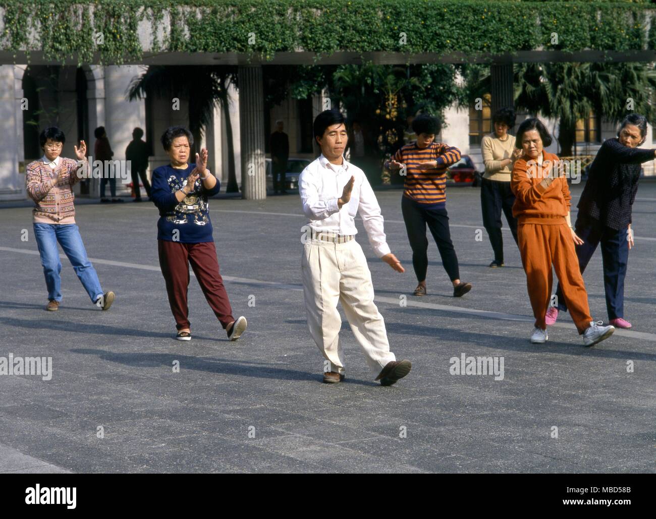 Chinese master of Tai Chi with his students in a park in Hong Kong Stock Photo