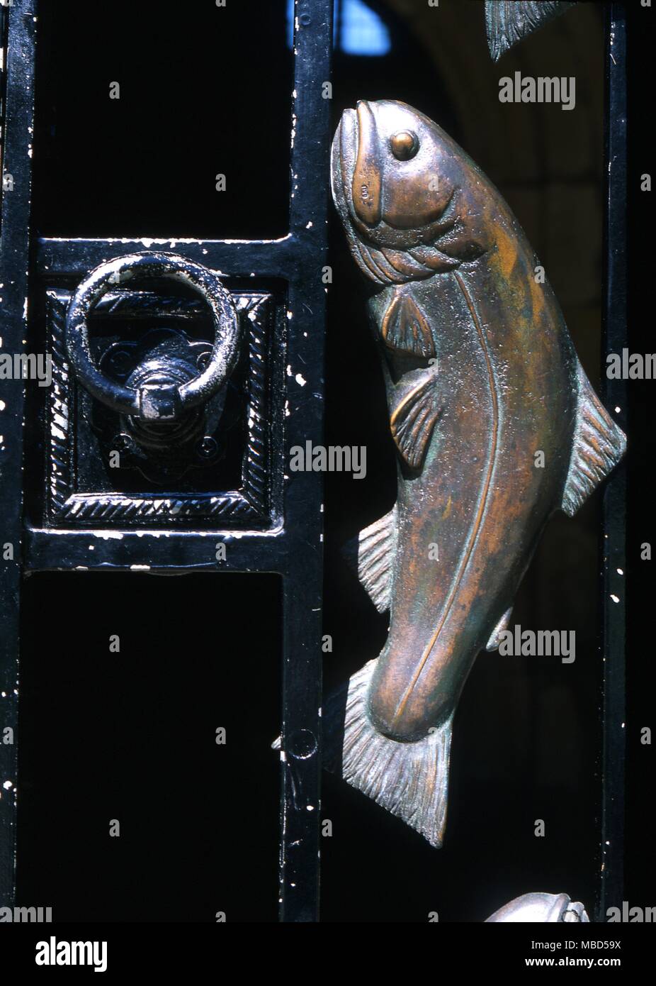Symbols - Fish. Fish, from a group of eight which decorate the metal porch gate of the church of St Michael. It is a symbol for Christ. Stock Photo
