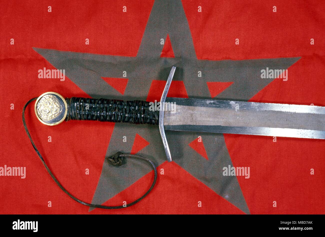 A ritual sword, used in the black mass and grimoire rituals. The hilt has been laid on the magical pentacle flag. Stock Photo
