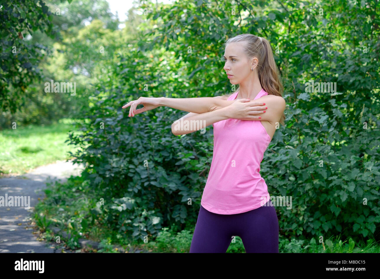 woman doing stretching exercise in park Stock Photo