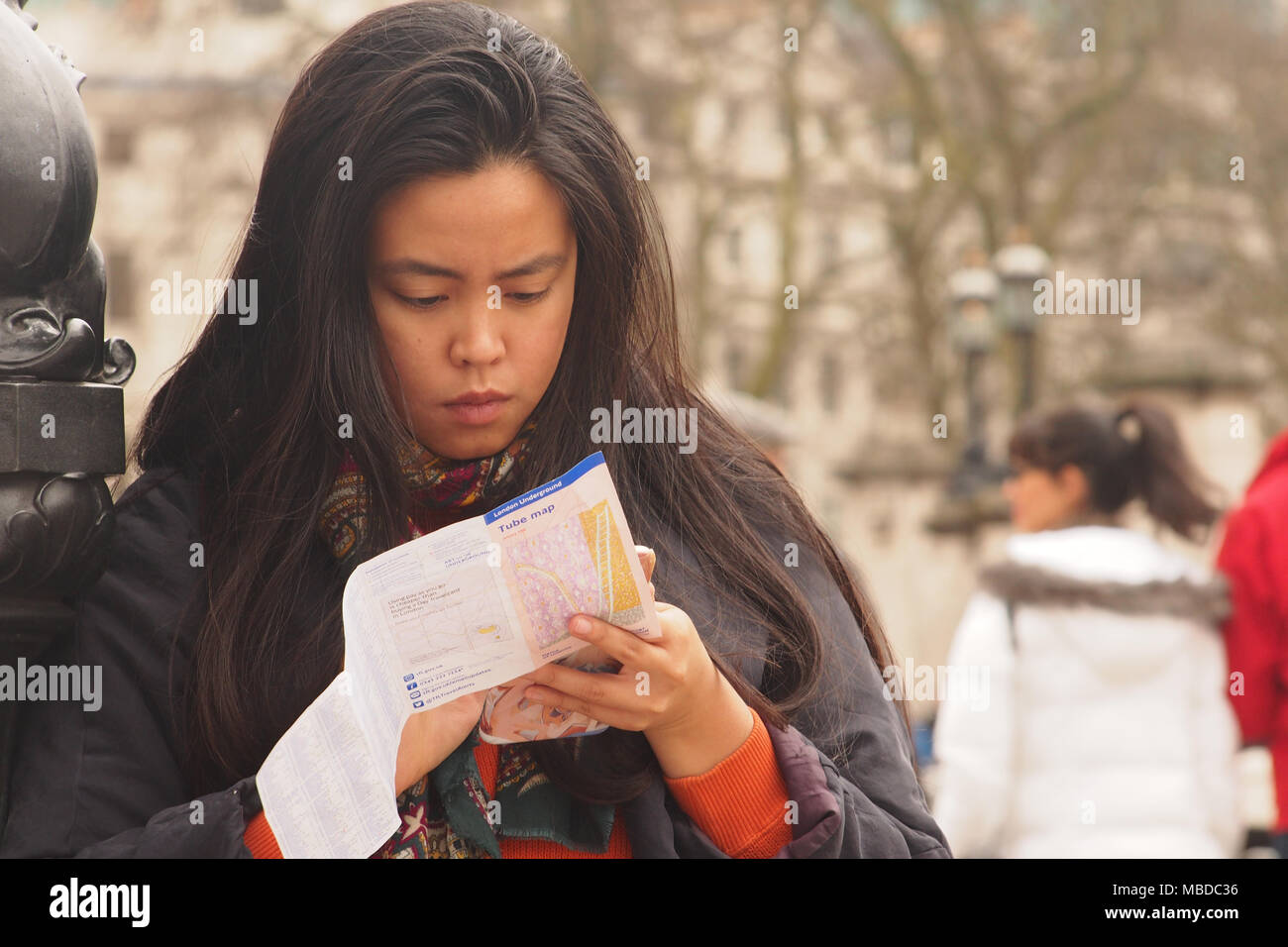 A young woman studying a handbag sized Tube map of the London Underground in Trafalgar Square, London Stock Photo