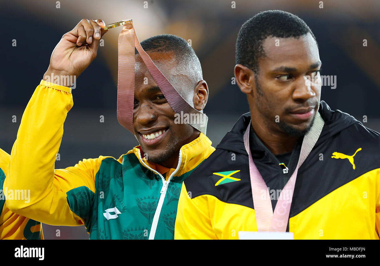 South Africa's Akani Simbine with  his gold medal (left) as Jamaica's Yohan Blake collects his silver won in the Men's 100m Final at the Carrara Stadium during day six of the 2018 Commonwealth Games in the Gold Coast, Australia. PRESS ASSOCIATION Photo. Picture date: Tuesday April 10, 2018. See PA story COMMONWEALTH Athletics. Photo credit should read: Martin Rickett/PA Wire. RESTRICTIONS: Editorial use only. No commercial use. No video emulation. Stock Photo