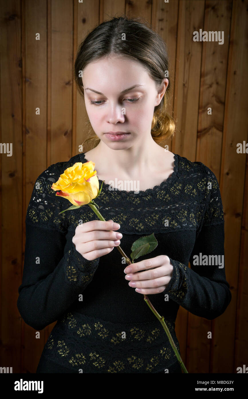 girl in black dress with yellow rose in hands Stock Photo - Alamy